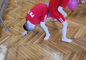 Chłopcy podają sobie balon między nogami