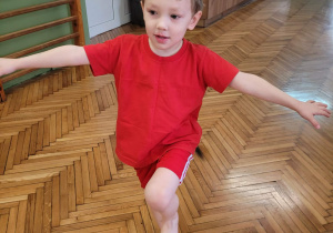 Chłopiec stoi na jednej nodze z woreczkiem na głowie