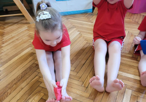 Dziewczynki robią skłony w przód z woreczkiem