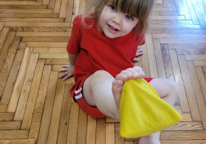 Dziewczynka podnosi woreczek palcami stóp