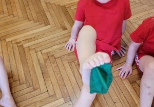 Dziewczyna podnosi zielony woreczek palcami stóp