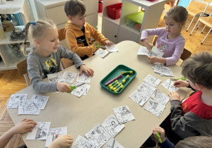 Dzieci przy stoliku wycinają nożyczkami