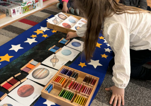 Dziewczynka kładzie niebieski kolor obok planety