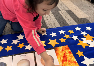 Dziewczynka układa żółty kolor obok Słońca