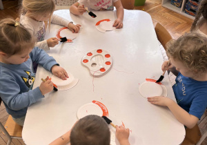 Dzieci przy stoliku malują talerzyki