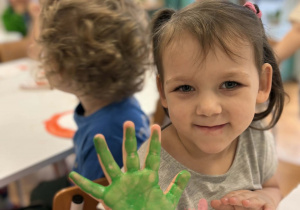 Dziewczynka pokazuje pomalowaną rękę na zielono
