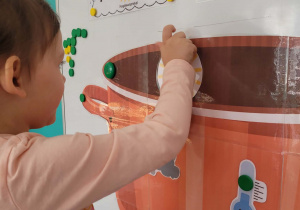 Dziewczynka przyczepia słońce na garnek