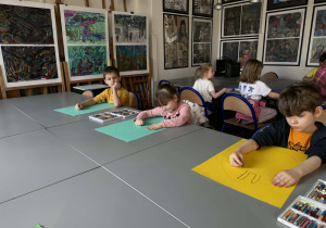 Dzieci siedzą przy stolikach i malują