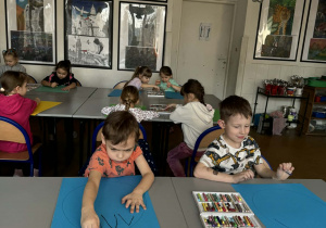 Chłopcy na kartonach malują królika