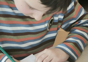 Chłopiec na szaro koloruje dinozaura