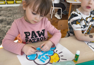 Dziewczynka wykleja chmurkę ze słoneczkiem