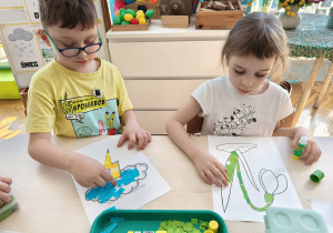 Chłopiec wykleja chmurkę burzową a dziewczynka przebiśniega