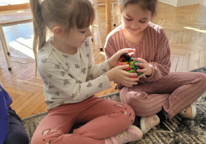 Dziewczynka przekauzje koleżance duży kłębek kolorowej włóczki