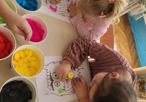 Dzieci przy stolikach wybierają kolory bibuły