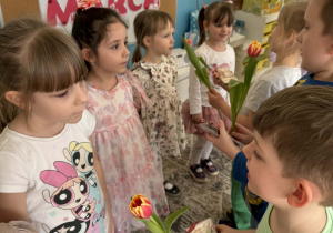 Chłopcy podają dziewczynkom kwiaty