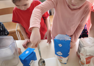 Dziewczynka wsypuję łyżkę maki do pojemnika