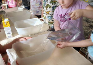 Dziewczynka wlewa wodę z dzbanka