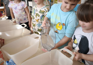 Chłopie wlewa wodę do pojemnika