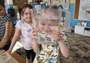 Chłopiec pokazuje rozmytą twarz przez pojemnik z wodą