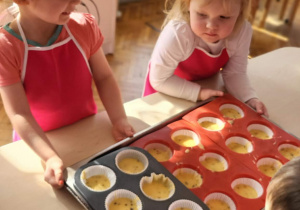 dziewczynki stoją przed babeczkami