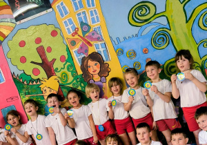 Dzieci siedzą pod grafiką z medalami