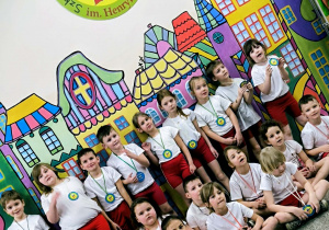 Dzieci siedzą pod logo szkoły 175