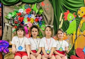 Dziewczynki siedzą na ławce z medalami