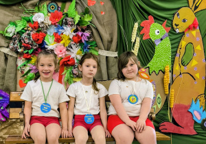 Trzy dziewczyni siedzą na ławce z medalami