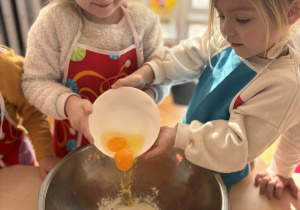 Dziewczynki dodają jajka do mąki