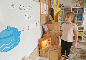 Dziewcyznka odczytuje napis w marcu jak w garncu