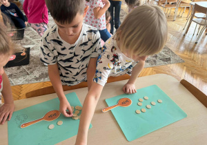 Chłopcy ukladają liczmany obok zadań na łyżkach matematycznych