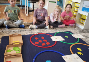 Dzieci siedza na dywanie przed zbiorami