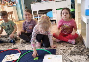 Dziewczynka wklada jedną zielona rybkę do zbioru