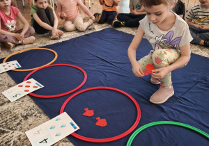 Dziewczynka układa w czerwonym zbiorze czerwone rybki