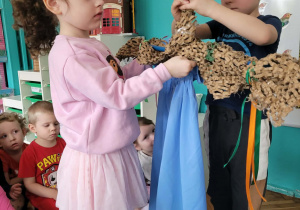 Dziewczynka zakłada długa niebieską spódnicę na kij Marzanny