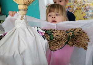 Dziewczynka zakłada Marzannie białą pelerynę