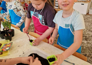 Dzieci nabierają ziemię na łyżki