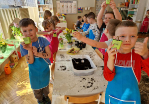 Dzieci pokazują doniczki z zasadzonymi cebulkami