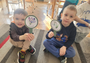 Chłopcy trzymają w rekach lupy z wiosennymi kwiatami