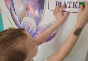 Chlopiec przyczepia napis płatki