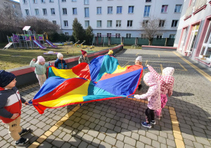 dzieci poruszają się z chustą animacyjną po kole