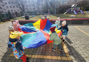 dzieci poruszają się z chustą animacyjną po kole