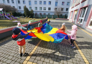 dzieci poruszają się z chustą animacyjną po kole