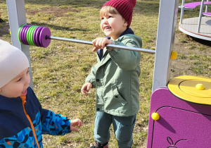 dzieci stoją przy sprzęcie do zabaw w ogrodzie