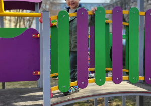 chłopiec stoi na kładce za płotkiem