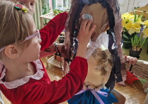 Dziewczynka przyczepia oczy Marzanny