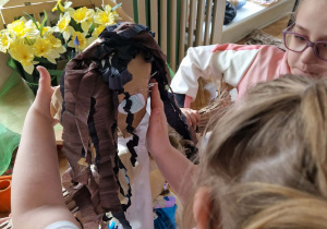 Dziewczynka przyczepia do głowy Marzanny oko