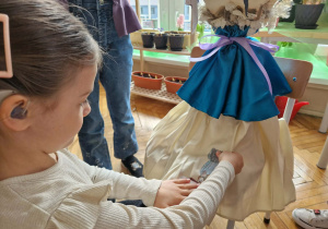 Dziewczynka przyczepia do sukni Marzanny bałwana