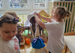 Dziewczynki zakładają na kukłę Marzanny chustę
