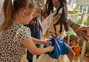 Dziewczynka przyczepia na suknię Maqrzanny śnieżnkę